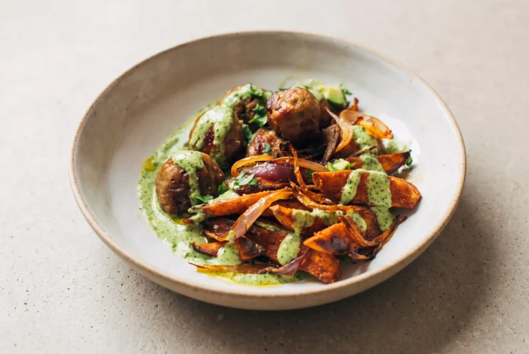 Avocado mojo bowl with sweet potato wedges, chicken meatballs, roasted onion, and cilantro avocado sauce