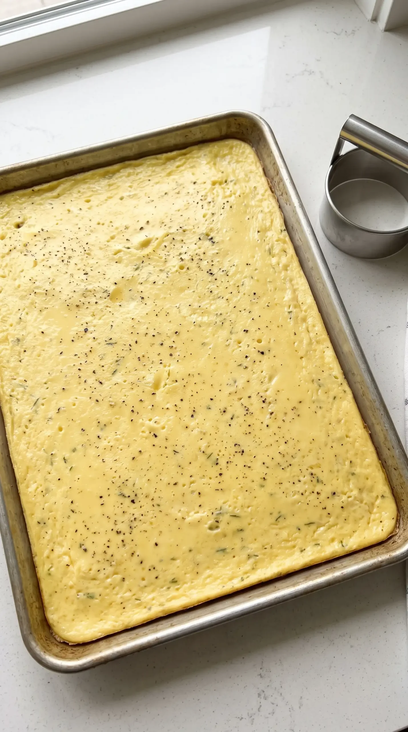 Baked egg layer on a sheet pan prepared for breakfast sandwich portions