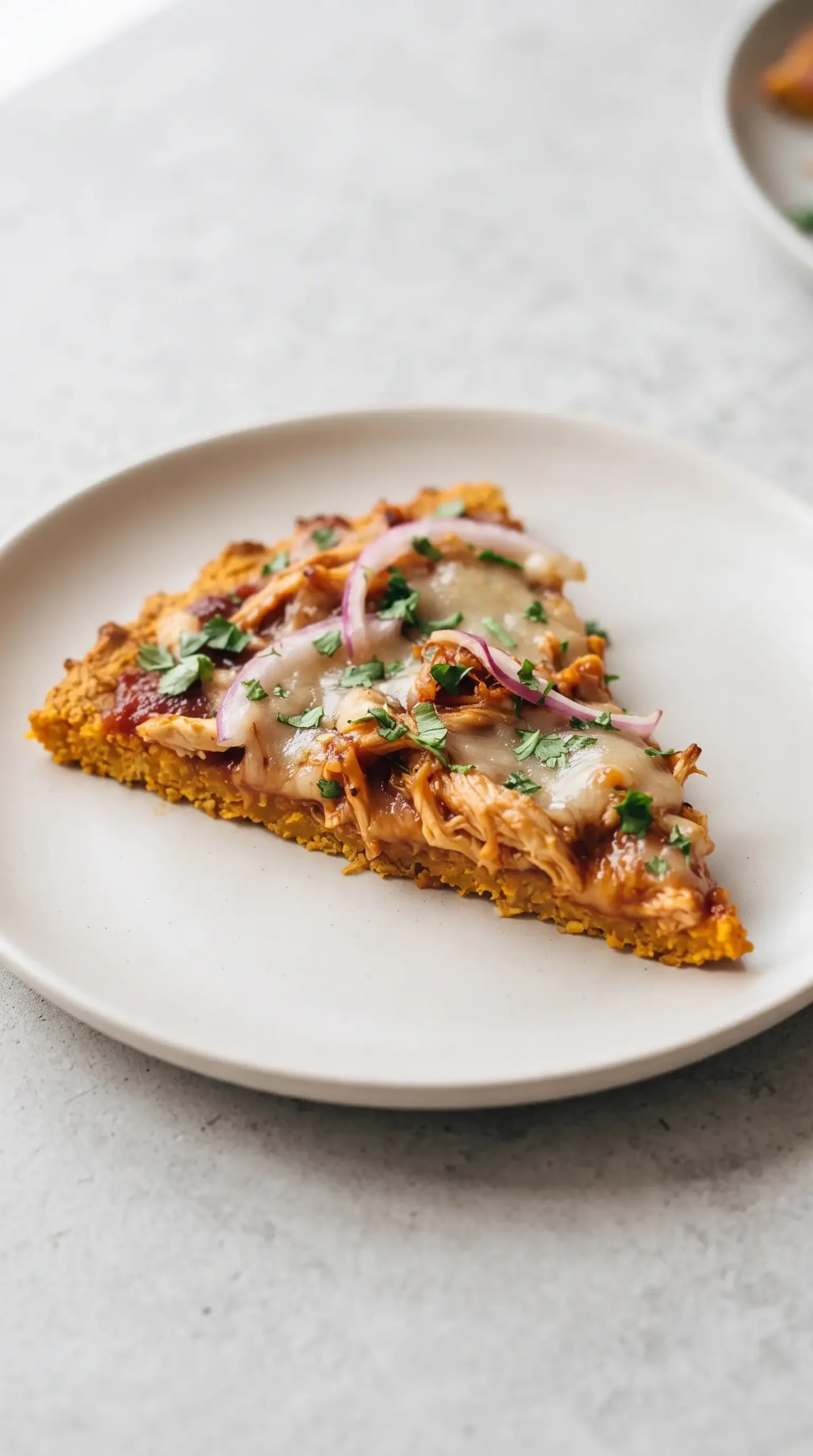 Slice of BBQ chicken pizza with sweet potato crust, mozzarella, onion, and cilantro