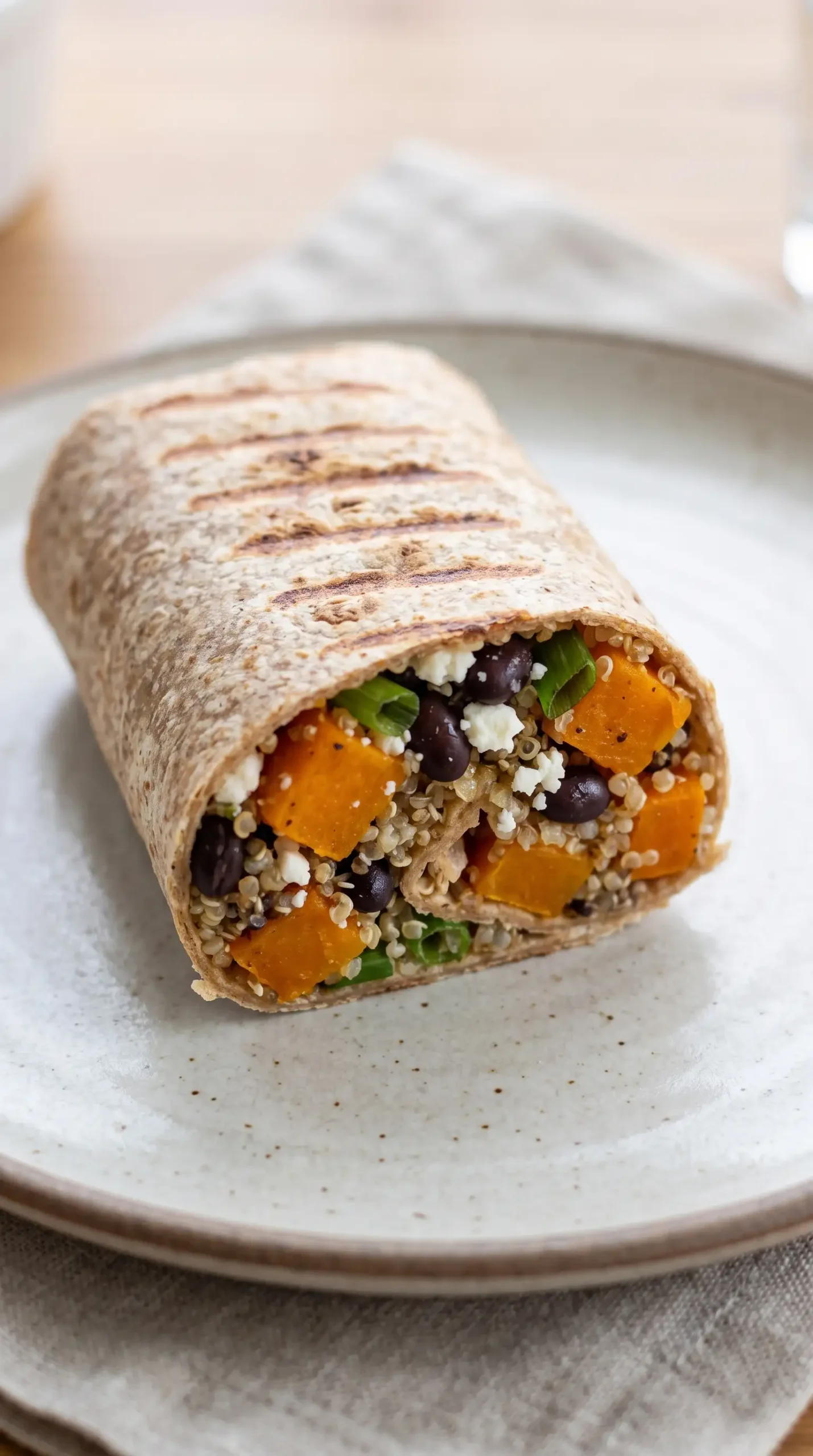 Cut butternut squash wrap showing quinoa, black beans, scallions, and cheese filling
