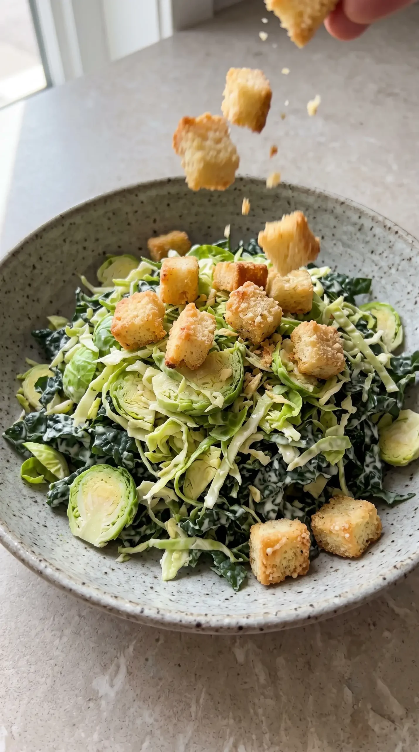 Golden cheezy garlic croutons added to a Brussels and kale Caesar salad bowl