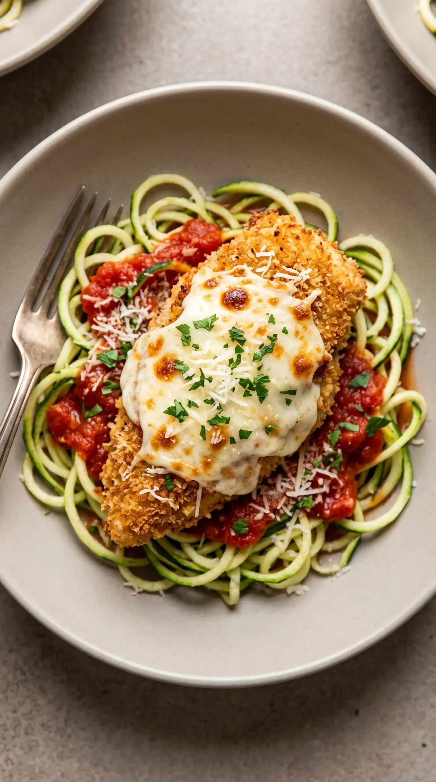 Healthy chicken parmesan served with zucchini noodles, tomato sauce, and melted mozzarella