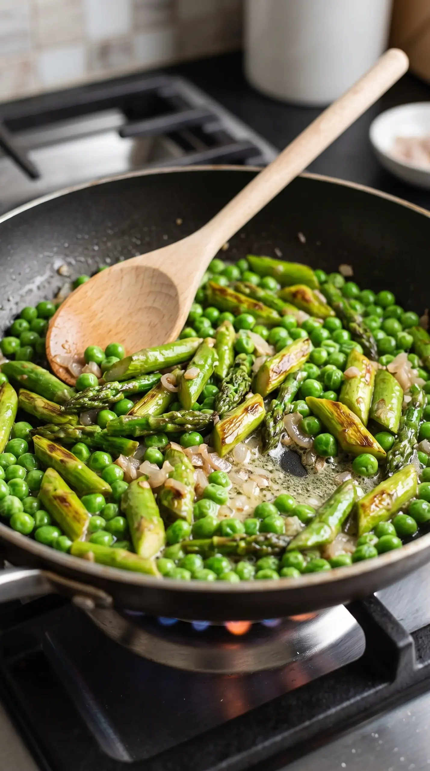Asparagus pieces sauteing with butter and shallot in a shallow pan