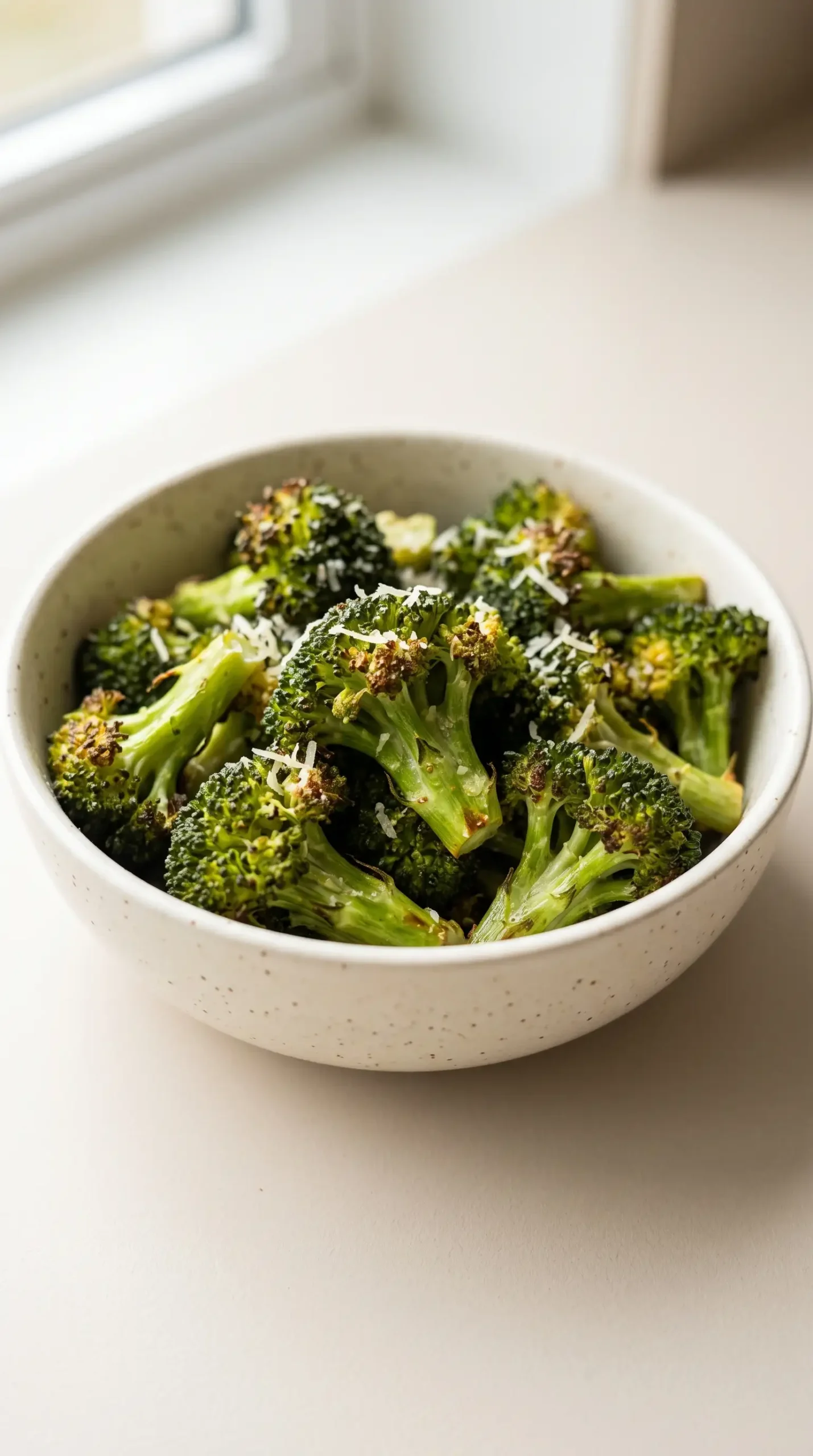 Roasted air fryer broccoli with browned edges and a light Parmesan topping
