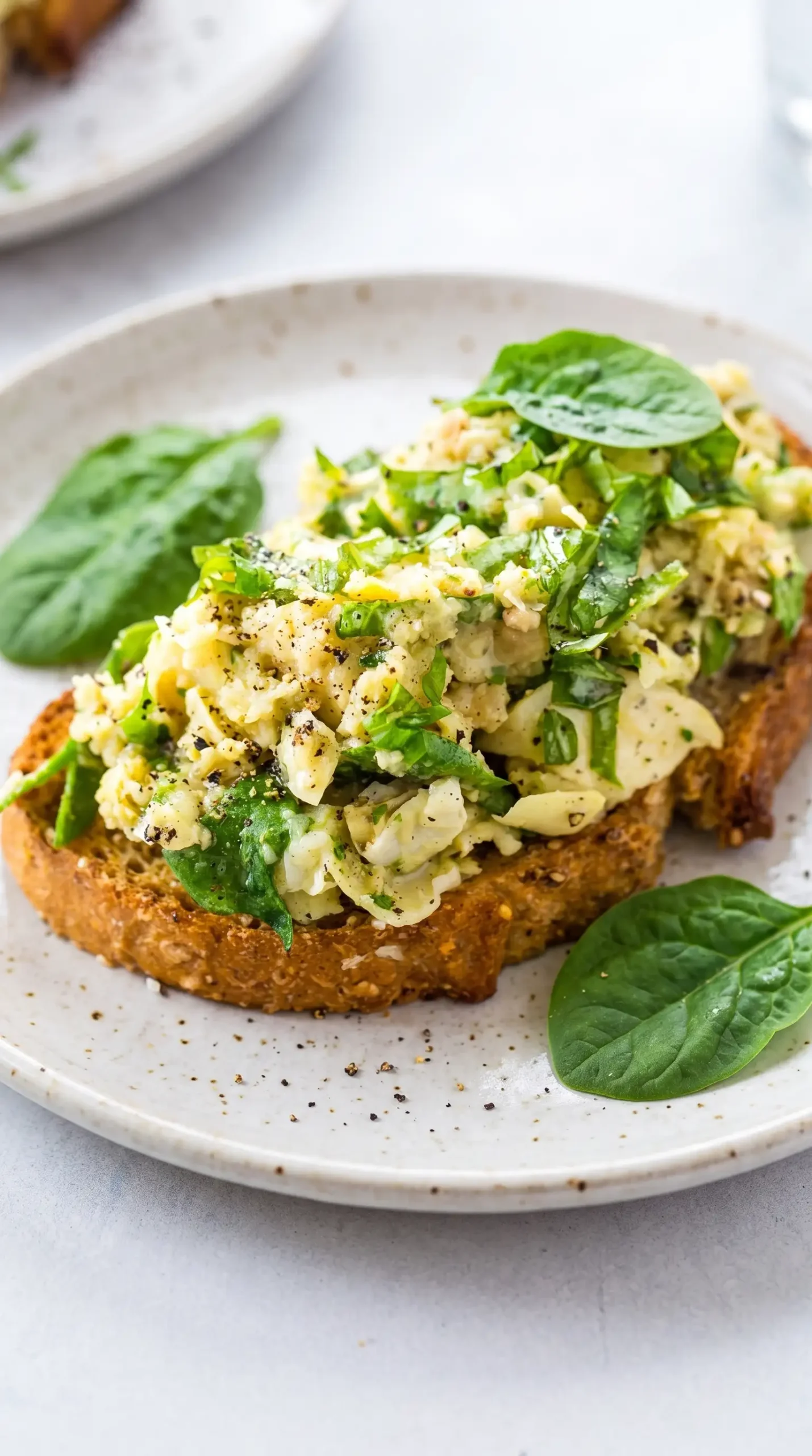 White bean toast with creamy artichoke spread, basil, and spinach topping