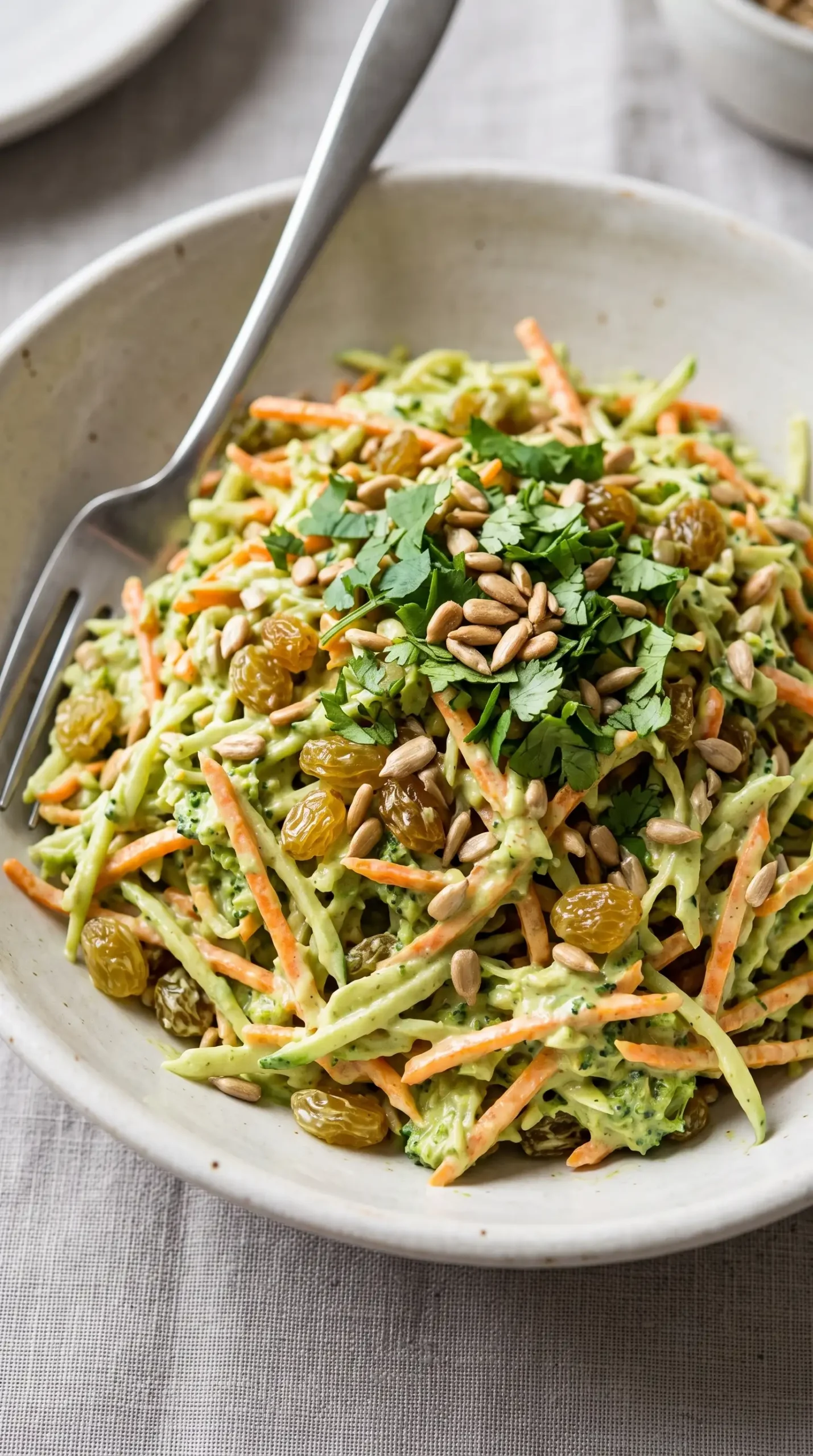 Serving bowl of green curry salad with creamy dressing, slaw, raisins, seeds, and cilantro