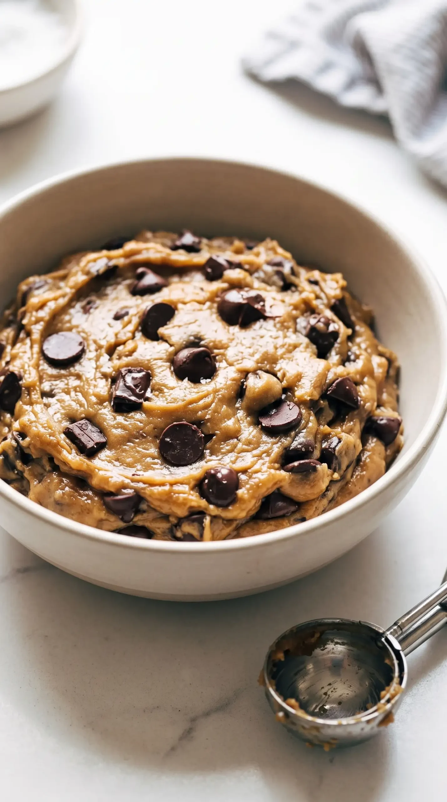 Rested brown butter cookie dough with chocolate chips in a mixing bowl