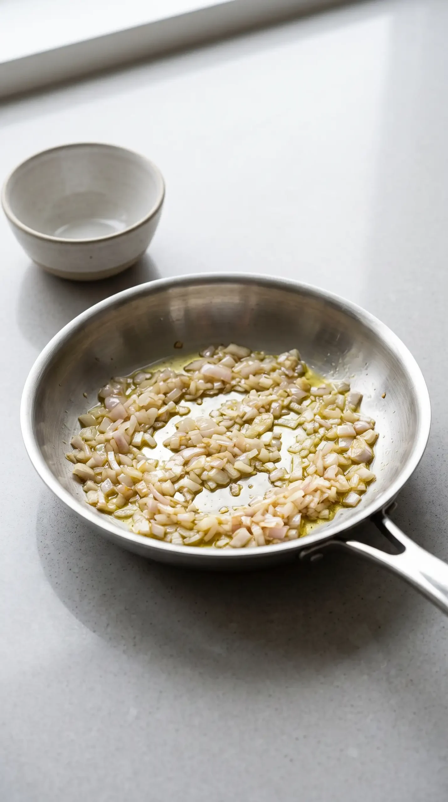 Finely chopped shallots sautéing in a small skillet for avocado blue cheese dressing