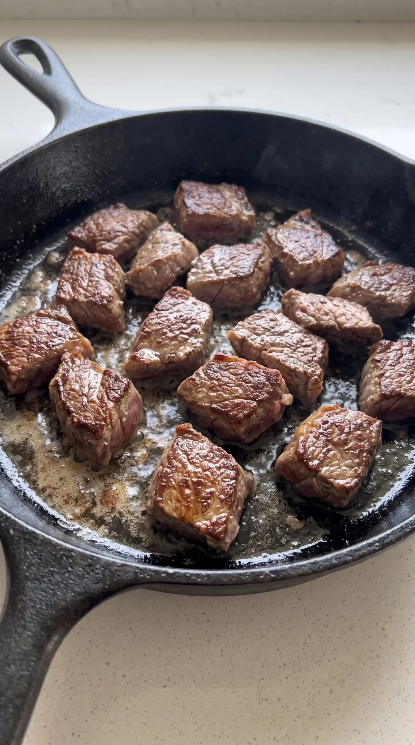 Bite-sized sirloin steak pieces searing in a skillet for vodka steak pasta