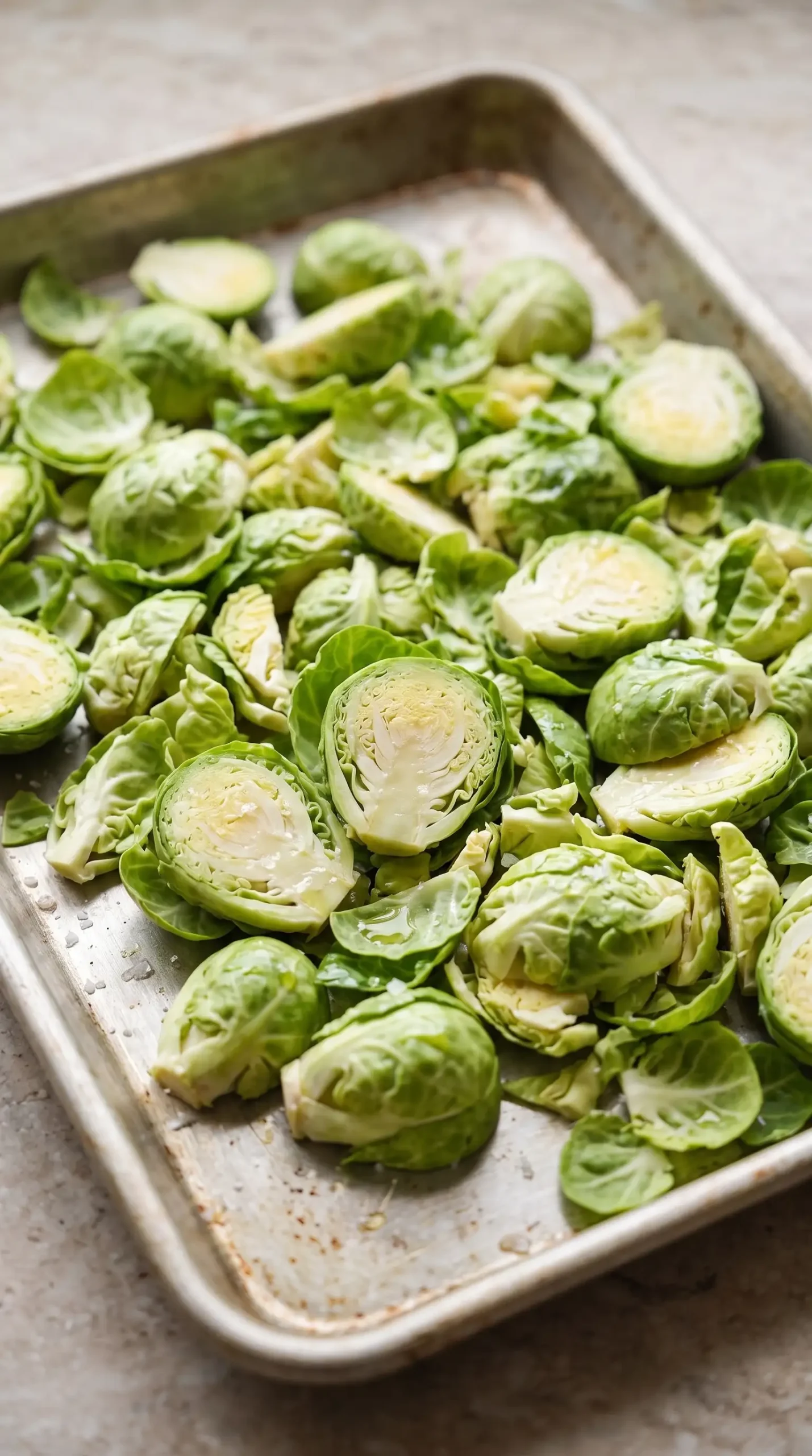 Shaved Brussels sprouts coated with oil and salt on a baking sheet ready for roasting