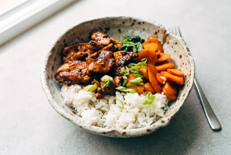 Spicy pork with sambal and soy sauce served over rice with carrots, spinach, and green onions